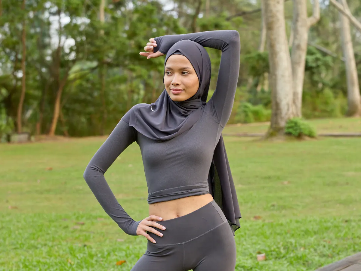 Woman stretching outdoors in modest charcoal activewear